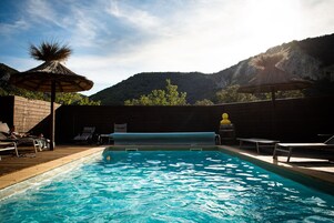 Una piscina al aire libre de temporada, sombrillas