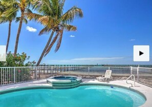 Une piscine avec un jacuzzi, des palmiers et une vue sur l’océan.