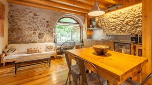 Un interior rústico con una mesa de madera, paredes de piedra y un arco de piedra.