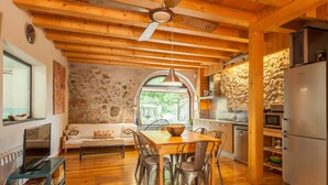 Un interior de madera con una mesa de comedor, sillas, un sofá, un televisor y electrodomésticos de cocina.