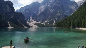 Un lago rodeado de montañas, un muelle de madera y un barco pequeño.