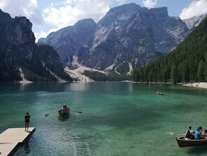 Un llac envoltat de muntanyes, un moll de fusta i una barca petita.