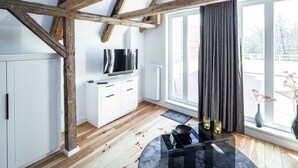 A modern kitchen with wooden beams, white cabinets, a black countertop, and a large window with curtains. - Apartment 1 Wohnen am Turm - Living at Schloßplatz (Oldenburg)