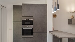 Una cocina moderna con horno empotrado, encimera e iluminación colgante.