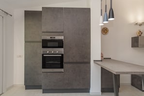Une cuisine moderne dotée d’un four encastré, d’un plan de travail et de luminaires suspendus.