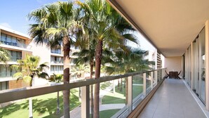 A balcony with a railing, a view of a courtyard with palm trees, and a building with multiple floors. - Apartamento Salgados Sol e Sal with Pool, Wi-Fi, A/C & Garden (Guia)