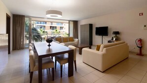 A modern living room with a dining area, a flat-screen TV, and a fire extinguisher. - Apartamento Salgados Sol e Sal with Pool, Wi-Fi, A/C & Garden (Guia)