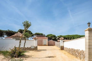 A gated entrance with a paved path leading to a building with a tiled roof. - Casa Torre de Meca 3 with Shared Pool, Terrace and Garden (Los Caños de Meca)