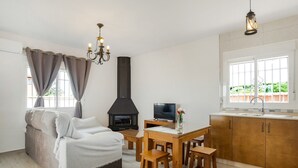 Una sala de estar acogedora con sofá, televisor, chimenea y zona de comedor con taburetes de madera.