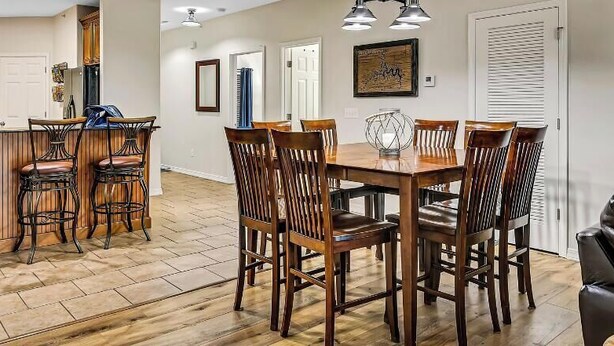 Un coin repas avec une table et des chaises en bois, une cuisine avec des tabourets de bar et un canapé en cuir.