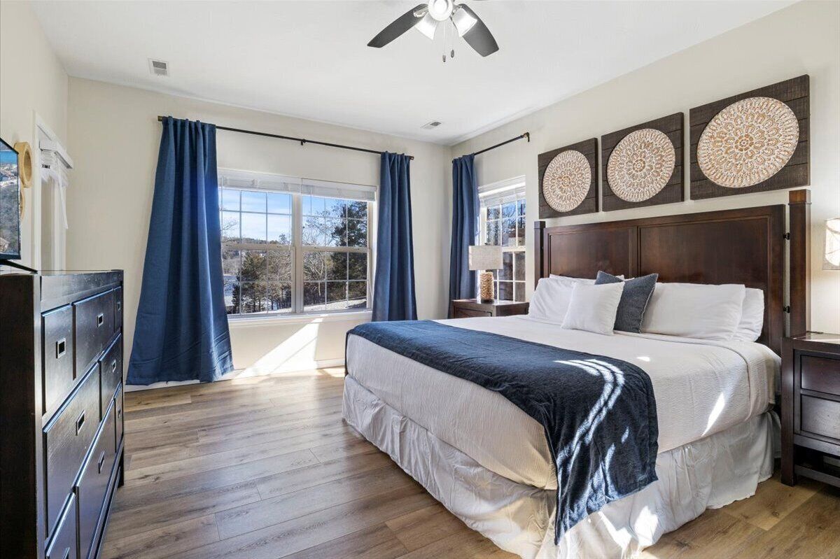 A bedroom with a large bed, wooden floor, and a view through the window.