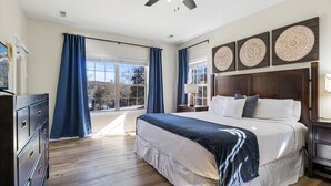 Une chambre avec un grand lit, un plancher en bois et une vue par la fenêtre.