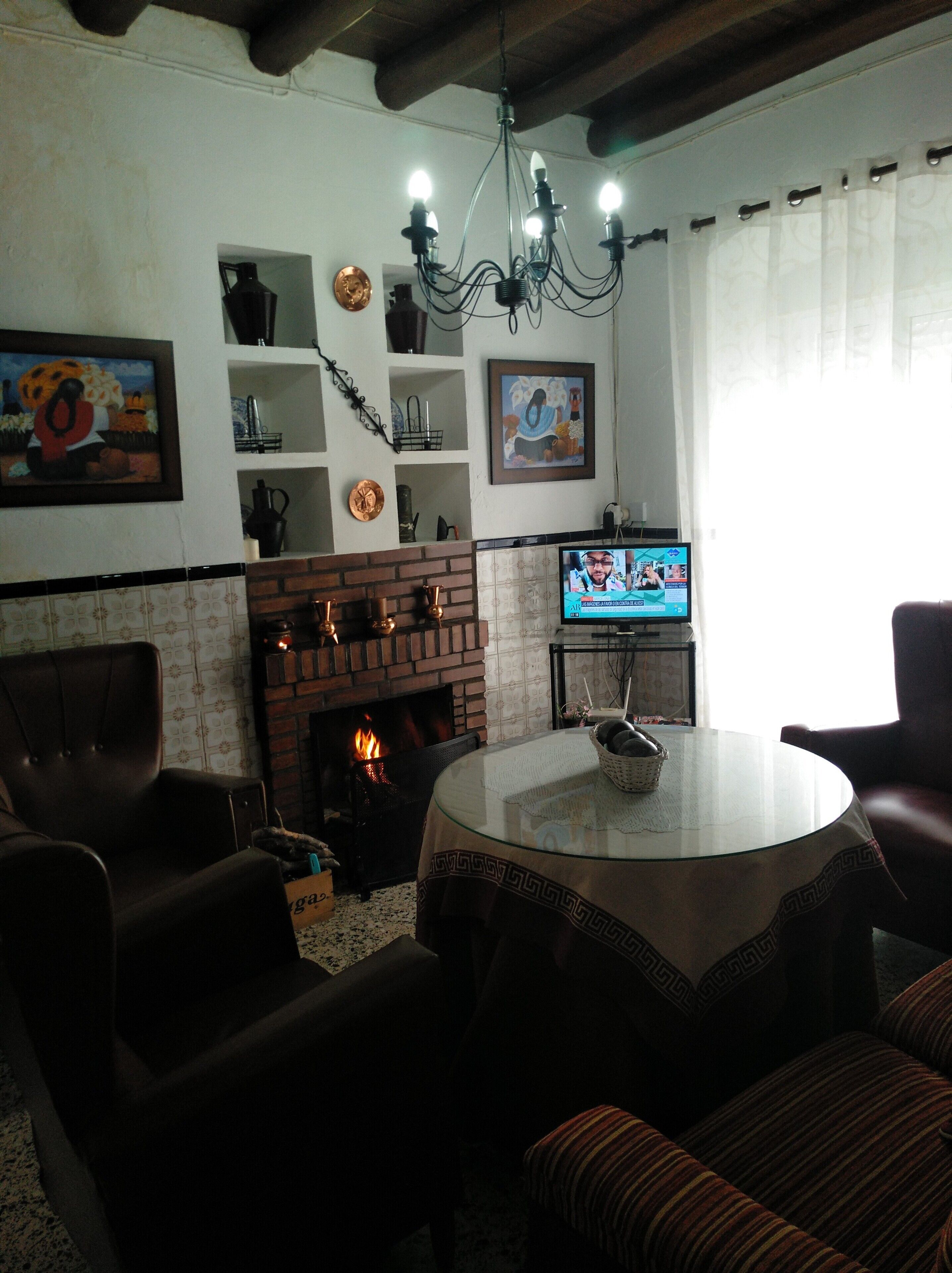 Een woonkamer met een open haard, een televisie en een kroonluchter.