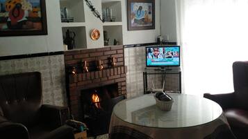 Een woonkamer met een open haard, een televisie en een kroonluchter.