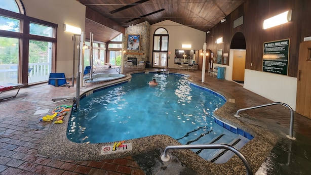 Ein Innenpool mit Steinwand, Whirlpool und einer Lounge mit Sesseln.
