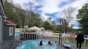 Ein Whirlpoolbereich mit Schwimmbecken, umgeben von einer Terrasse und einem Zaun.