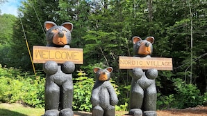 Drei Bärenstatuen halten Schilder mit den Aufschriften 'WELCOME' und 'NORDIC VILLAGE'.