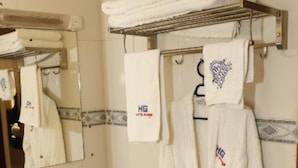 A bathroom with a sink, a mirror, and a robe hanging on a rack. - Goshen Inn Eldoret (Eldoret)