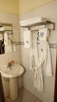 A bathroom with a sink, a mirror, and a robe hanging on a rack.