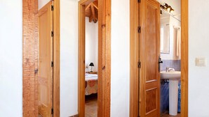 A hallway with wooden doors leading to a bedroom and a bathroom. - Charming Casita Torre de Meca 1 with Terrace, Garden, and Wi-Fi (Los Caños de Meca)