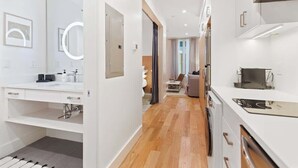 A modern hotel room with a bathroom, kitchenette, and a hallway leading to a living area. - The Iris, Signature Suite (Charleston)