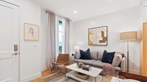 A modern living room with a sofa, coffee table, and a lamp. - The Iris, Signature Suite (Charleston)