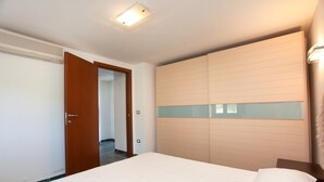 Une chambre d’hôtel avec un lit, une armoire, une porte et un luminaire.