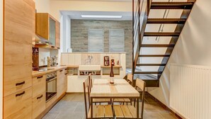 A modern kitchen with wooden cabinets, a dining table, and a staircase.