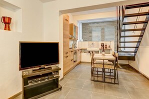 Une cuisine moderne équipée d’un téléviseur, d’une table à manger et d’un escalier.