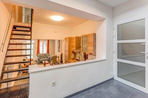 Un intérieur moderne avec un escalier, un coin repas et une grande fenêtre.