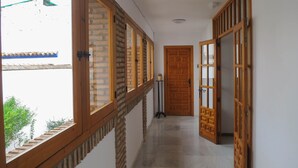 Un corridoio con porte di legno, una finestra che dà su un edificio e un tavolino con una pianta.