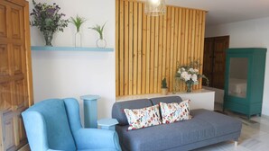 Un soggiorno con un divano grigio, poltrone blu, un pannello parete in legno a listelli e un mobile azzurro.