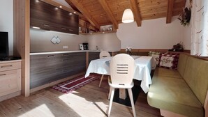 Une cuisine chaleureuse avec des poutres en bois, une table à manger avec des chaises et un canapé.