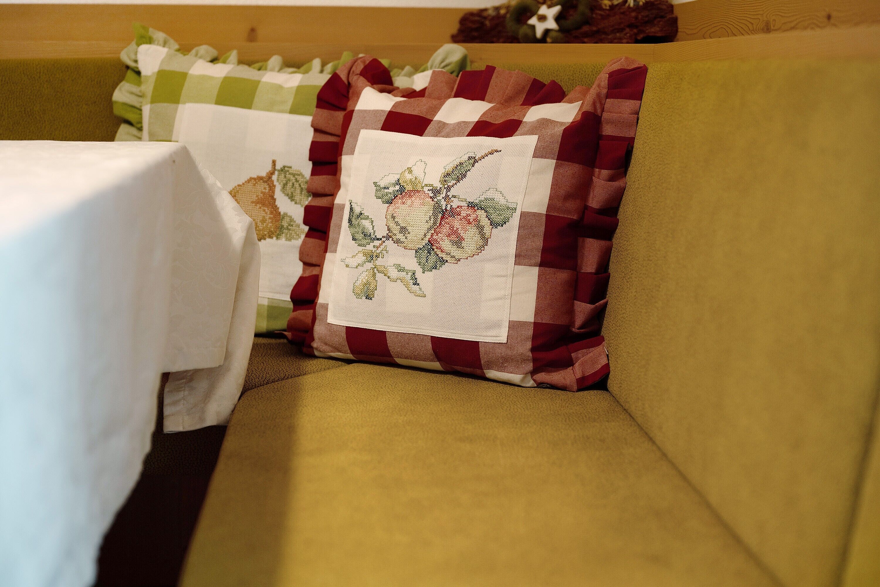 Ein Sofa mit Tischdecke und zwei Kissen mit Kreuzstich-Motiven.