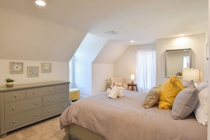 A bedroom with a bed, a dresser, a chair, a lamp, and a mirror. - Heated Saltwater Pool Hot Tub! (Eastham)
