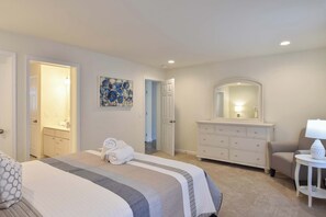 A hotel room with a bed, a dresser, a mirror, a painting, and a lamp. - Heated Saltwater Pool Hot Tub! (Eastham)