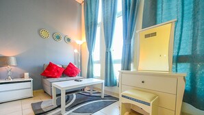A modern bedroom with a bed, bedside table, lamp, and a dresser. - SND - Bright and Spacious Studio (Dubai)