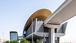 A modern building with a unique curved roof and a large overhang. - SND - Bright and Spacious Studio (Dubai)