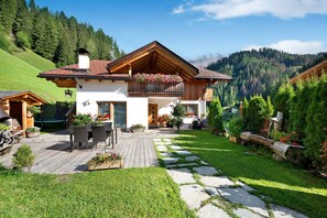 Eine Chalet mit Holzbalkon, Sitzgelegenheiten im Freien und Blumenkästen.