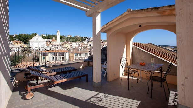 Terraço no telhado com pérgola, assentos e mesa com cadeiras.