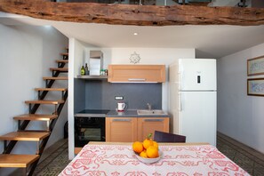 Een keuken met houten kastjes, een witte koelkast, een spoelbak en een tafel met een schaal fruit.