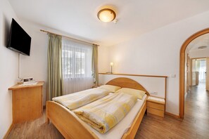 A bedroom with a bed, bedside tables, a TV, a lamp, and a mirror. - Idyllic Apartment 'Innerwalten 200' with Mountain Views, Restaurant & Parking (Walten)