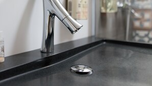 Une salle de bain moderne avec un robinet élégant et incurvé, fixé sur un plan de toilette noir.