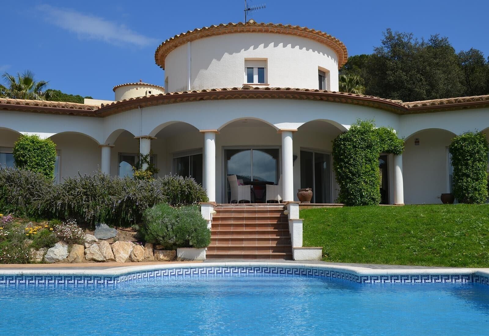 A Mediterranean-style villa with a swimming pool, a covered patio, and a well-maintained garden.
