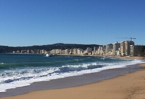 A beach with waves, a clear sky, and a cityscape in the background. - Villa Blanca-------- (Calonge)