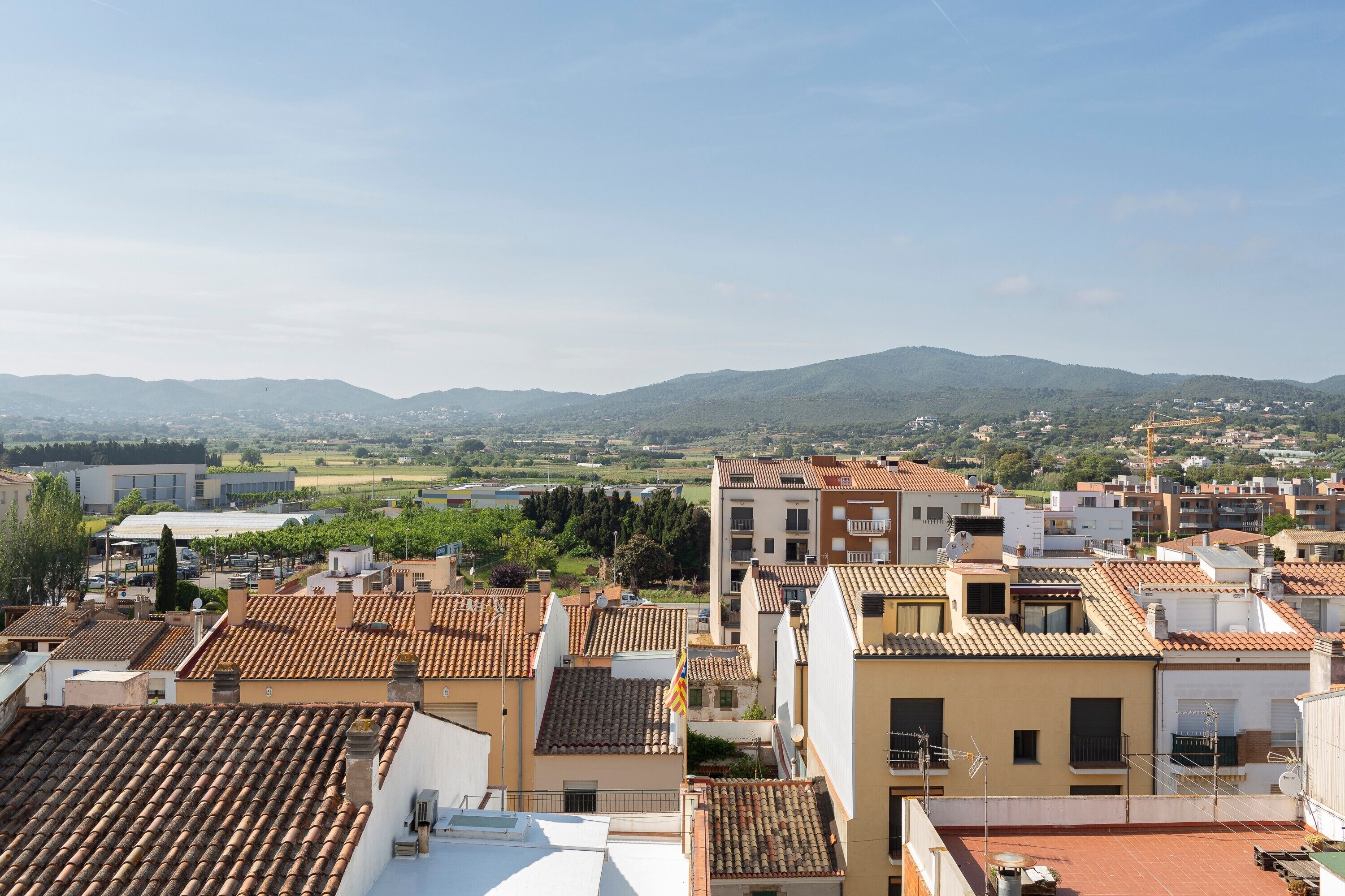 Una zona residencial con tejados de tejas de color terracota, una mezcla de arquitectura moderna y tradicional, y una vista distante de colinas verdes.