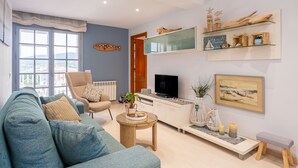 A living room with a sofa, armchair, TV, and decorative items. - Sunset Apartment on the Paseo de Mar in Front of the Beach with Wi-Fi (Sant Antoni de Calonge)