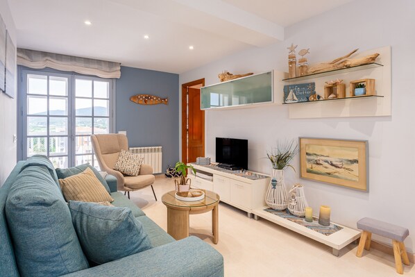 A living room with a sofa, armchair, TV, and decorative items.