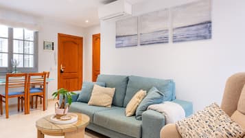 Una sala de estar con un sofá, una mesa de centro y un comedor con sillas.