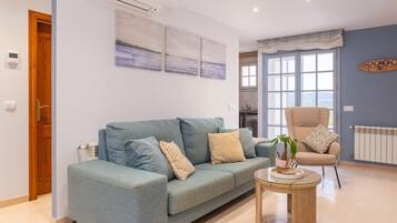 Una sala de estar con un sofá, un sillón y una mesita redonda.
